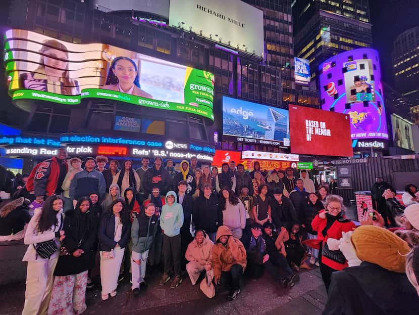 High school students pose in front of a building in Times Square.
