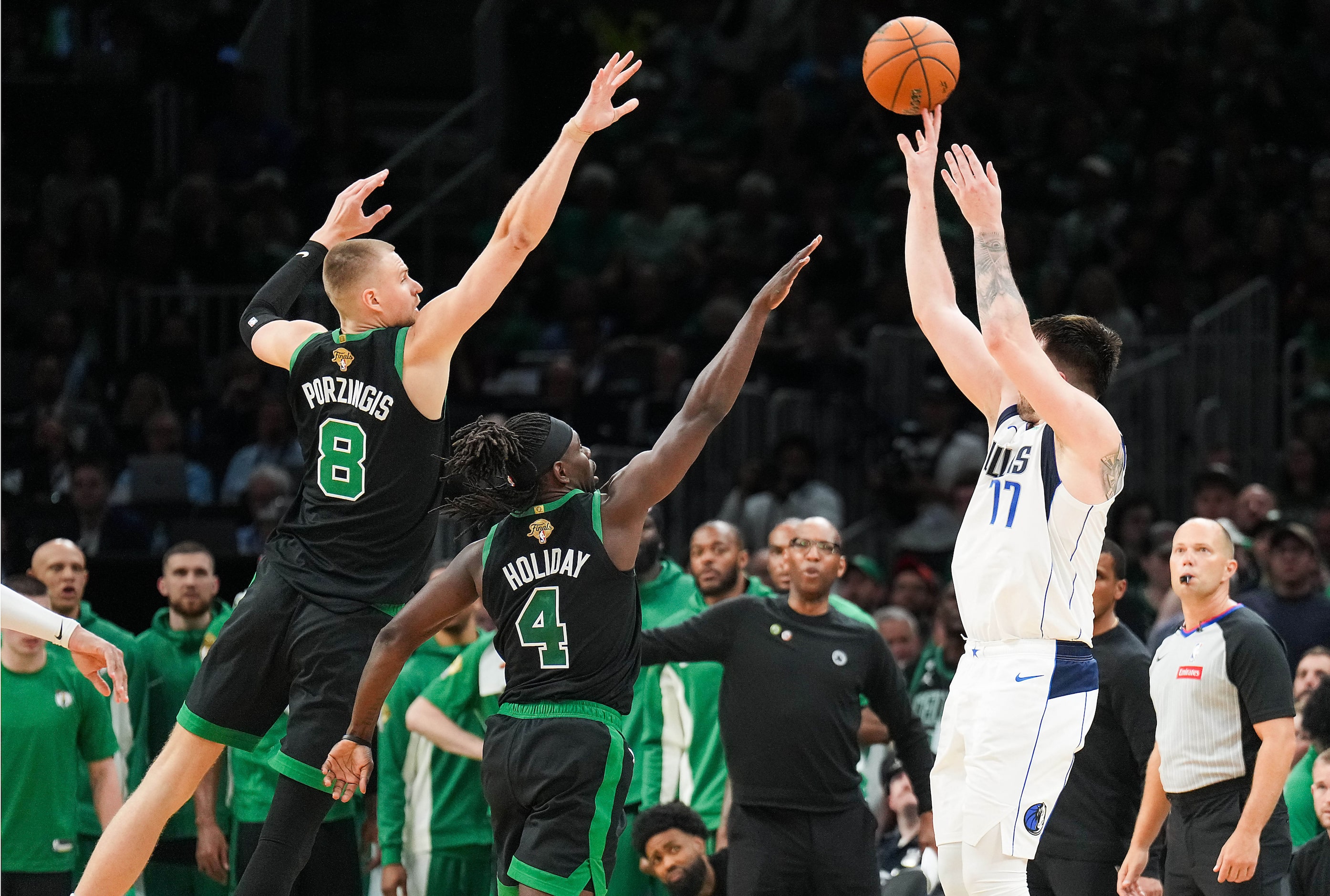 Dallas Mavericks guard Luka Doncic (77) shoots over Boston Celtics guard Jrue Holiday (4)...