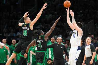 Dallas Mavericks guard Luka Doncic (77) shoots over Boston Celtics guard Jrue Holiday (4)...
