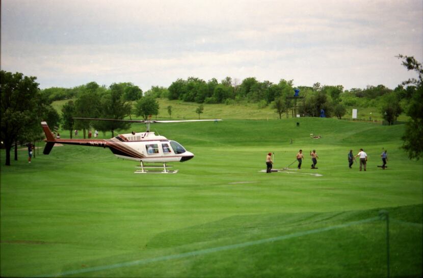 Shot May 12, 1994 - Workers and a helicopter try to  dry out the fairway on Hole #10 at the...