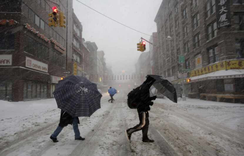 Pedestrians used umbrellas as they walked through falling snow in the Chinatown neighborhood...