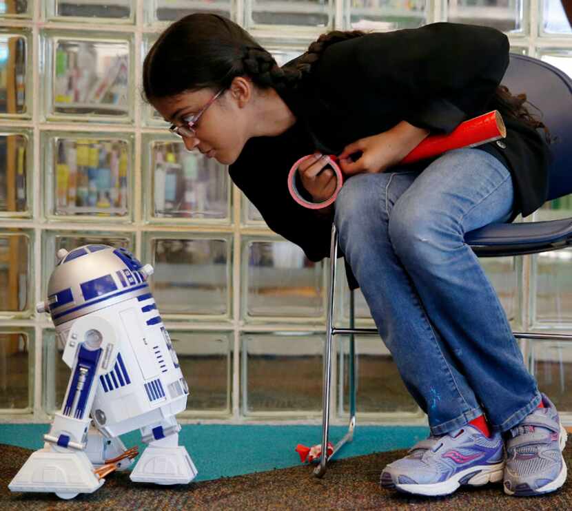  Sahib Kaur, 10, of Plano, Texas, gazes at an R2-D2 self-animated toy while she makes a...