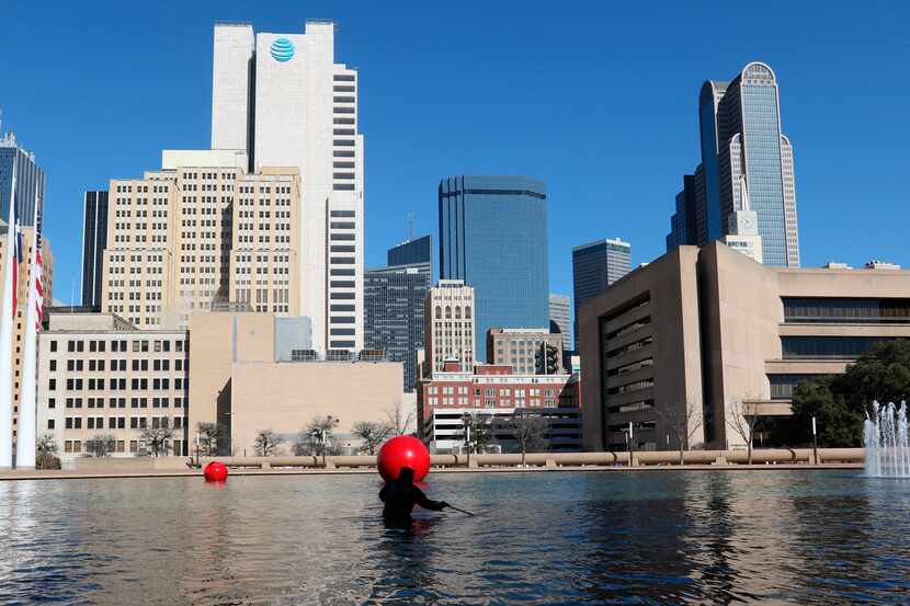 City of Dallas employee Kenneth Argusta cleans the reflecting pool at Dallas City Hall in...