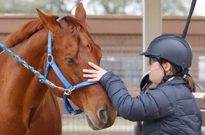 Sara "Happy" Waterman pets Scooter, one of the horses at ManeGait Therapeutic Horsemanship...