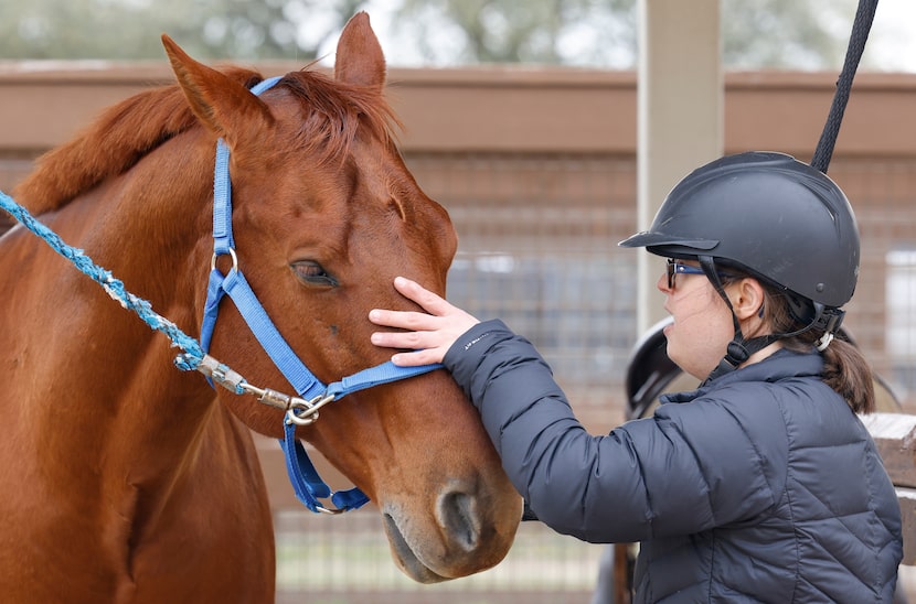 Sara "Happy" Waterman pets Scooter, one of the horses at ManeGait Therapeutic Horsemanship...