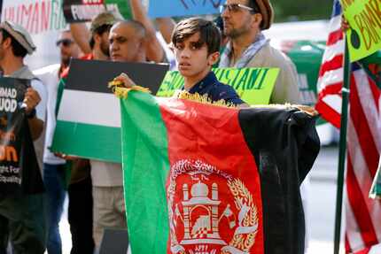 Sahib Faizi, 12, holds an Afghan flag during a demonstration outside of Sen. John Cornyn's...