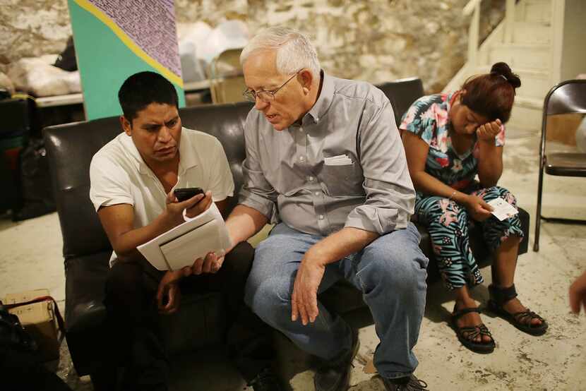 Ruben Garcia, center, director of the Annunciation House in El Paso,  speaks on a cell phone...