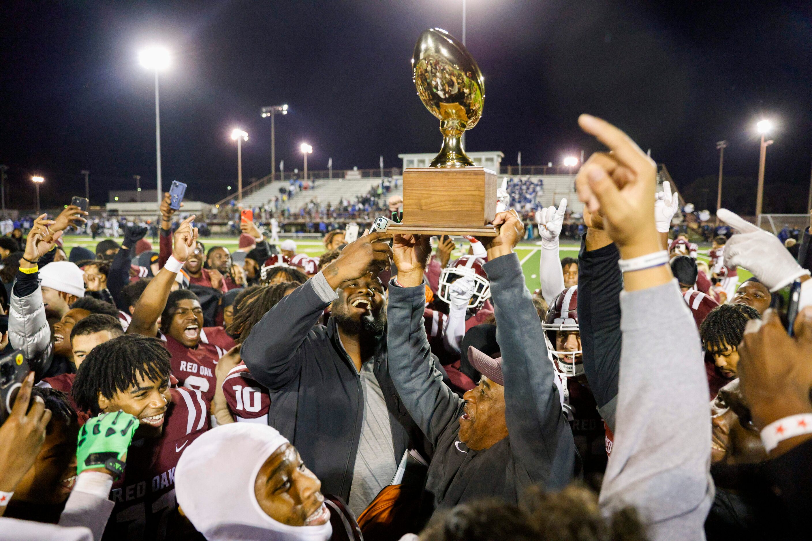 Red Oak head coach Melvin Robinson (center) raises the UIL District 4-5A Division I trophy...