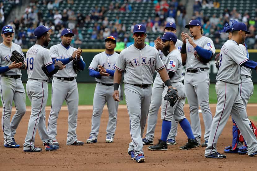 Texas Rangers' Adrian Beltre, center, is applauded by teammates as he walks off the field...