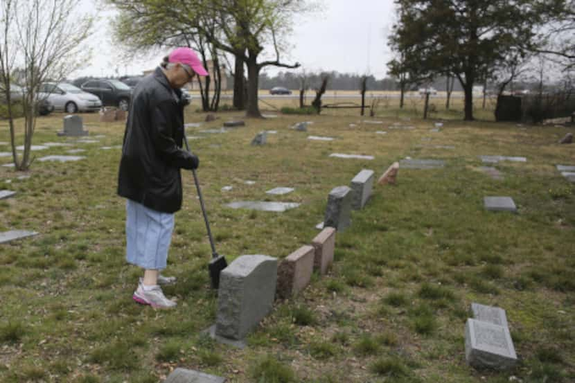 Sherry Johnston swept leaves and dirt away from a tombstone during Saturday's cleanup at the...