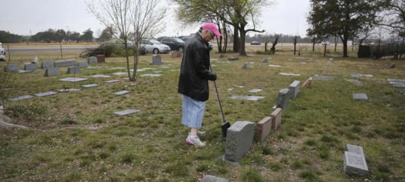 Sherry Johnston swept leaves and dirt away from a tombstone during Saturday's cleanup at the...