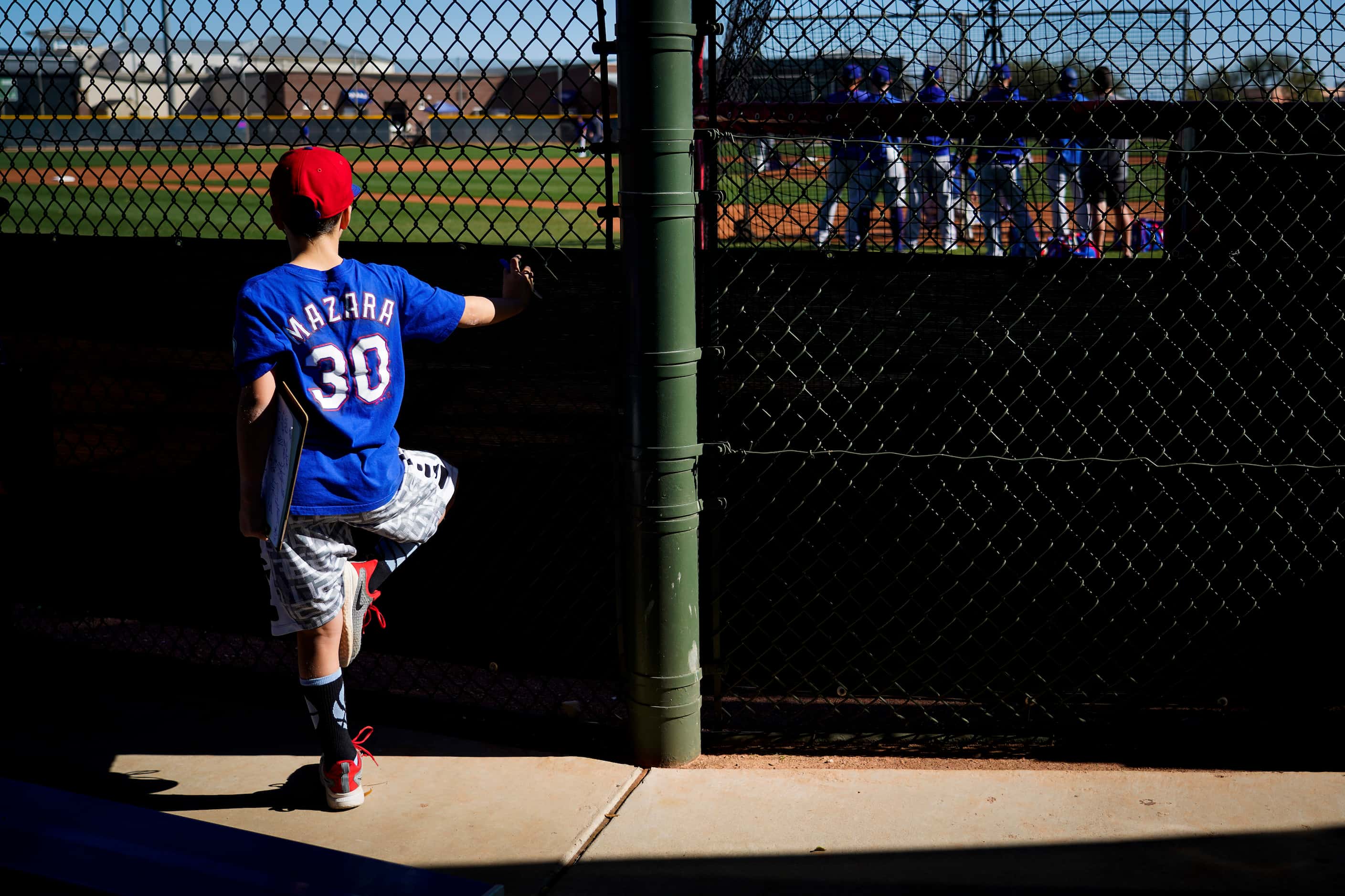 A young fan watches Texas Rangers pitcher Jonathan Hernandez throw live batting practied...