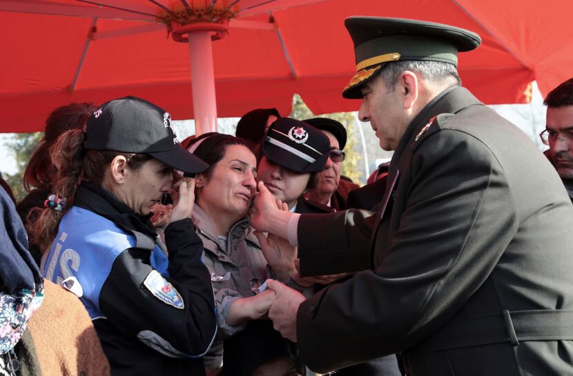 A relative is comforted by an army commander as family members attend funeral prayers for...