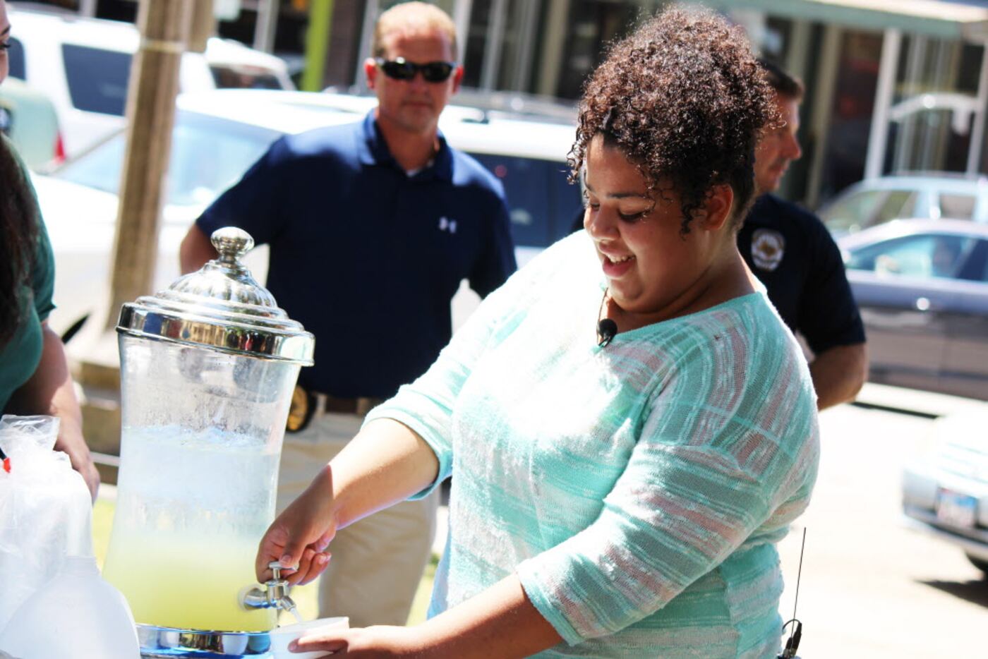 Mia Cagle fills a cup of lemonade for a Denton officer Thursday on the lawn of the Denton...