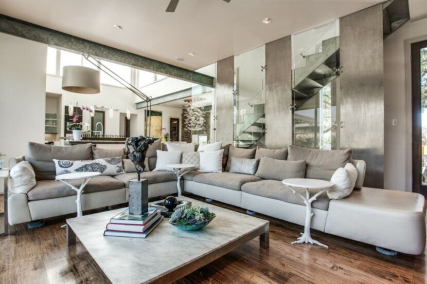 Exposed metal I-beams and a stainless-steel staircase with a Lucite hand rail complement the...