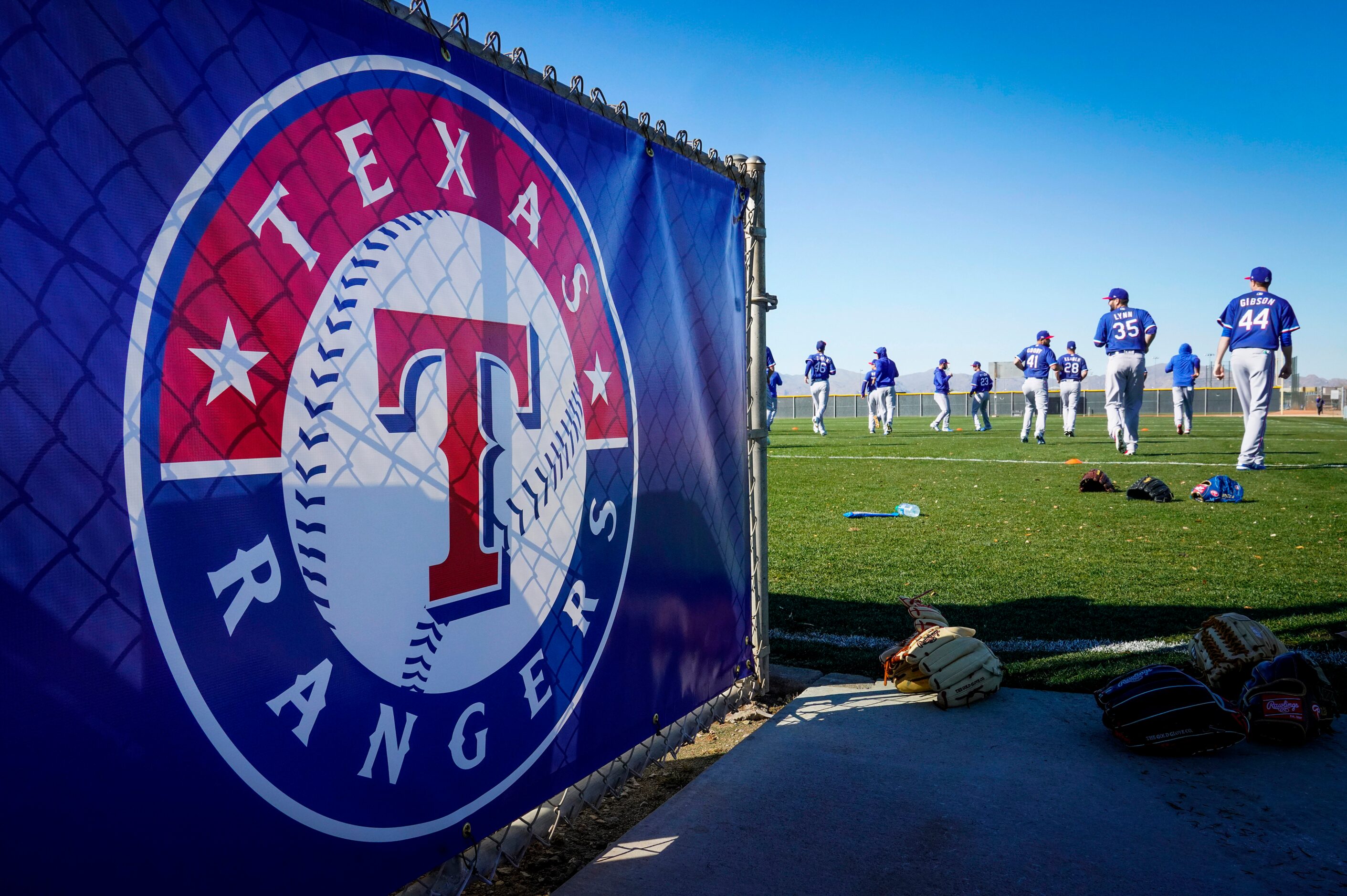 Texas Rangers pitchers and catchers stretch on a conditioning field during a training...