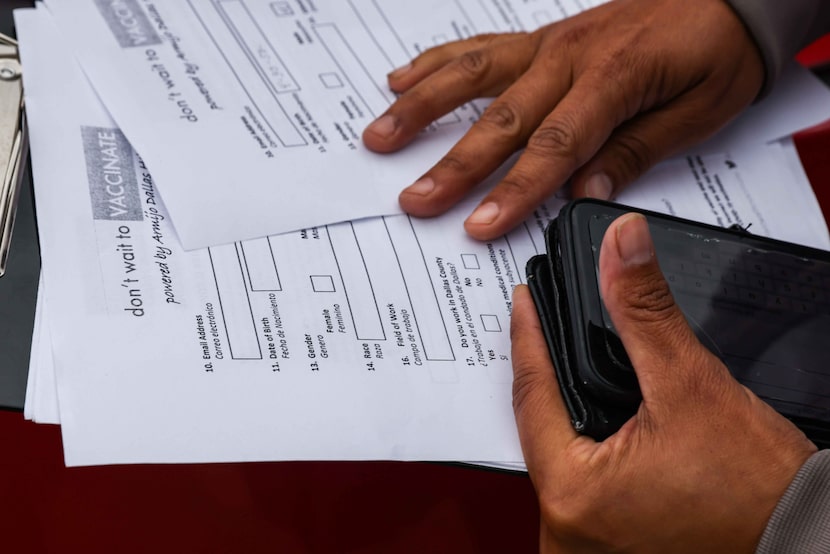 Leslie Armijo hands out forms to people in line at Santa Teresita Catholic Church in Dallas...