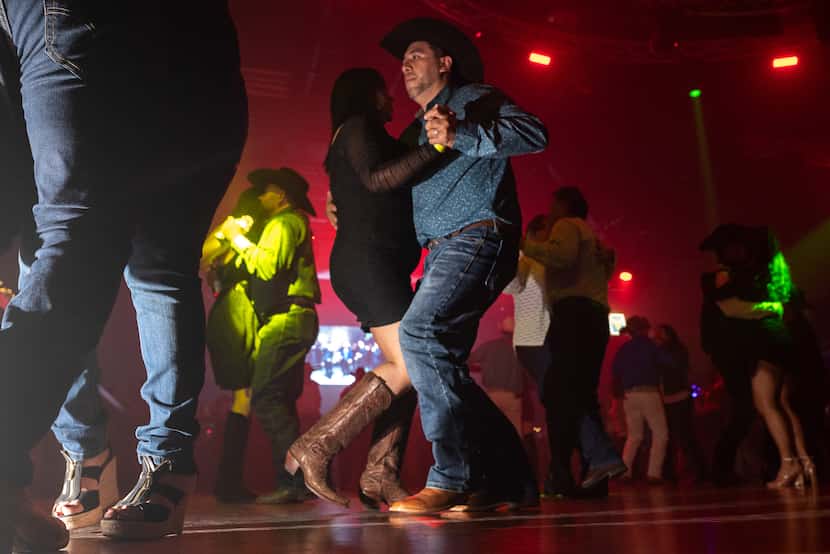 A couple dances while wearing square boots on the dance floor of Rodeo West Dallas, on...