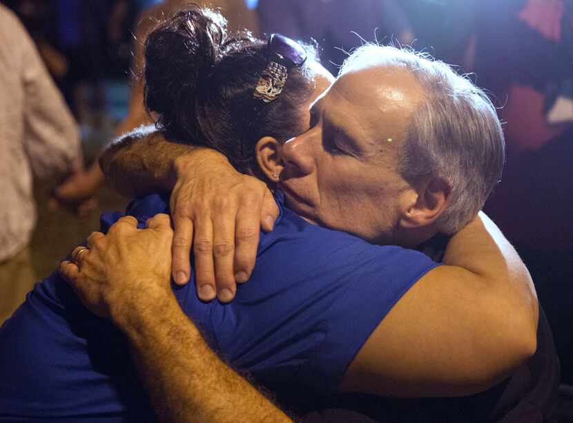 Governor Greg Abbott comforts a local resident during a candlelight vigil Sunday following...