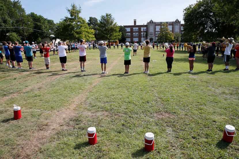 The Woodrow Wildcat Band goes through drills on its practice field across the street from...