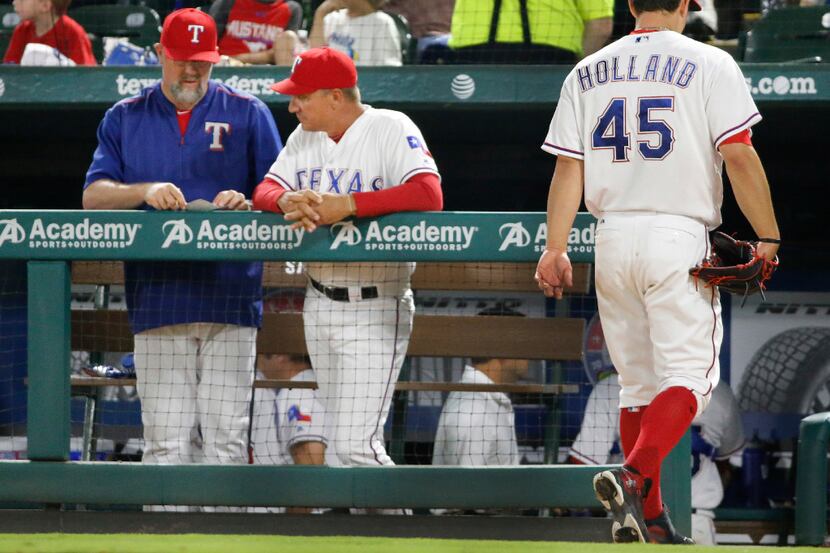 Texas Rangers starting pitcher Derek Holland (45) walks to the dugout past manager Jeff...