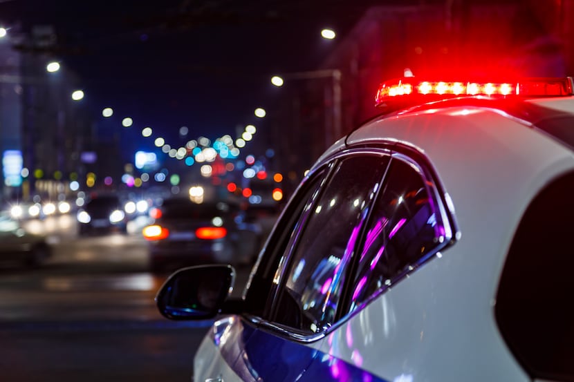 police car lights at night in city with selective focus and blurry car traffic in the...