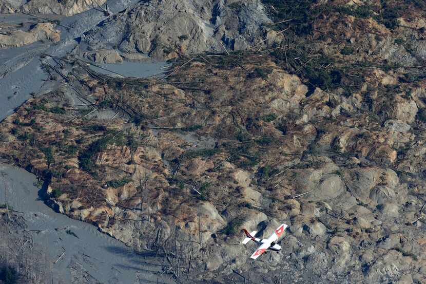 A Civil Air Patrol plane flies over the massive mudslide that killed at least 14 people and...