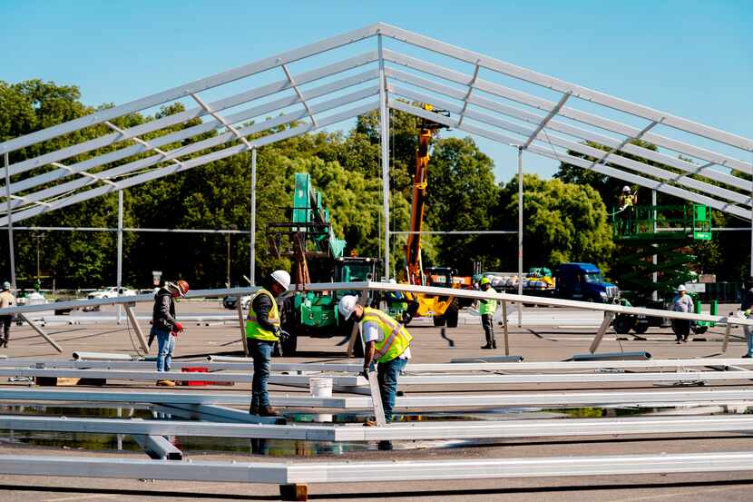 FILE — Workers erect a hangar-sized tent, Sept. 27, 2022, in the parking lot of Orchard...