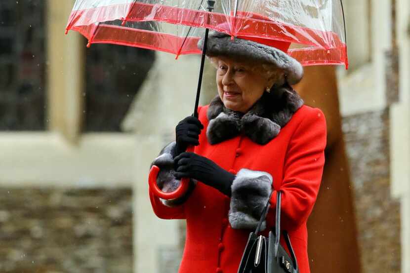 Britain's Queen Elizabeth II shelters under an umbrella as she leaves, after attending the...