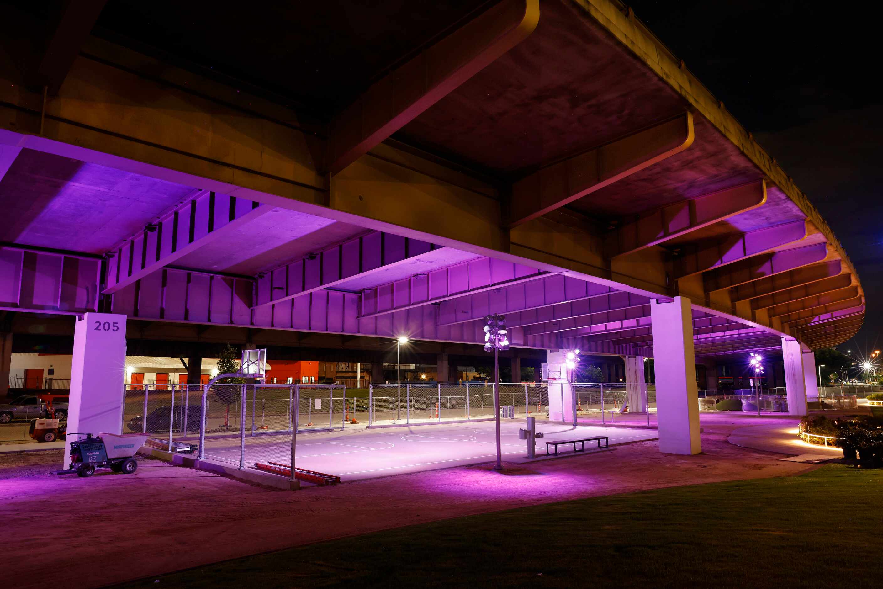 A basketball court awash in colored light is pictured under the I-345 overhead in the newly...