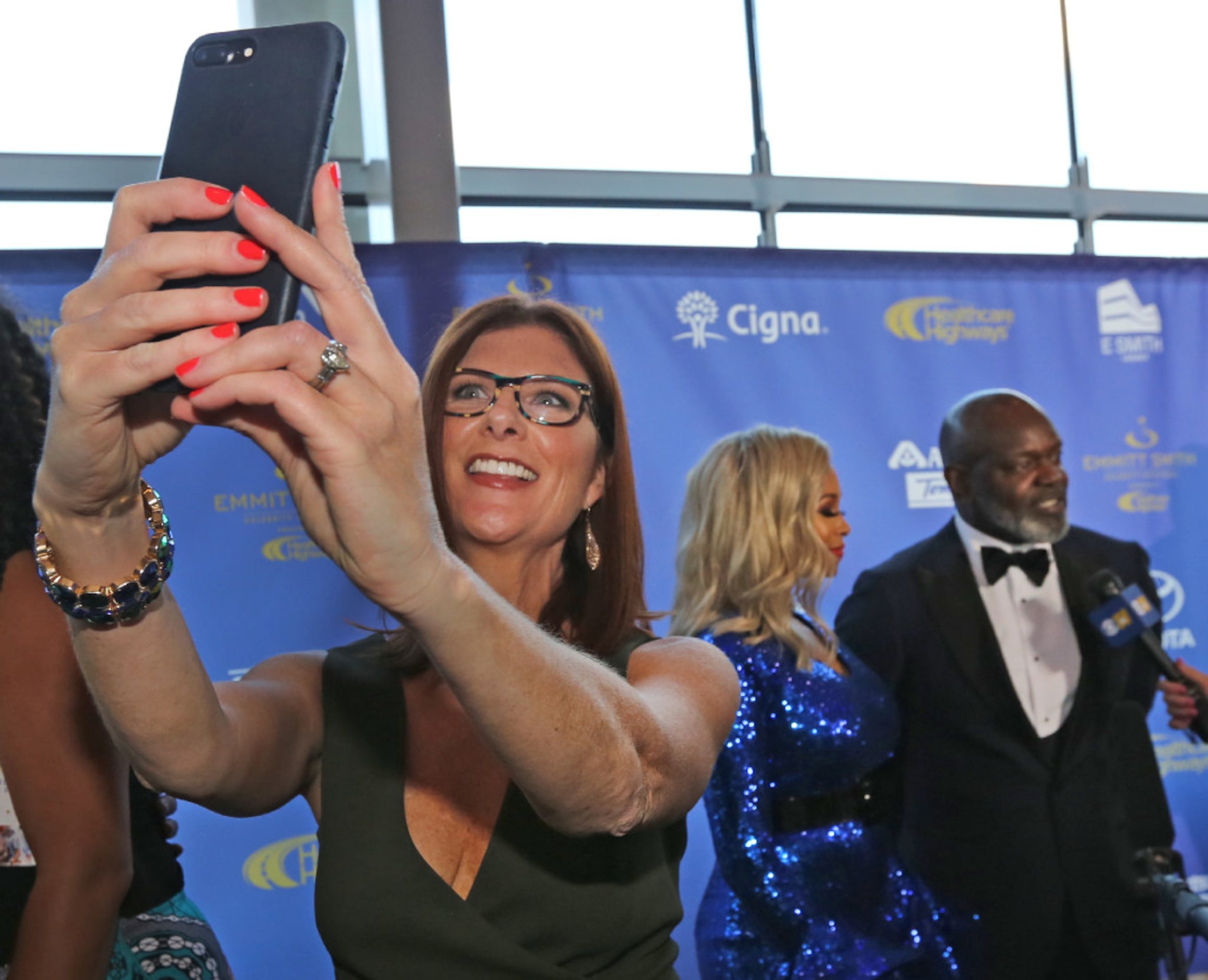 Cynthia Smoot grabs a selfie as the media interviews Pat and Emmitt Smith during the red...