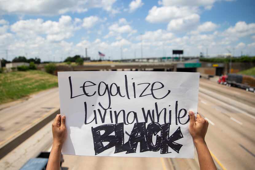 A protestor with the National Injustice Peaceful Rally holds a sign over the E R L Thornton...