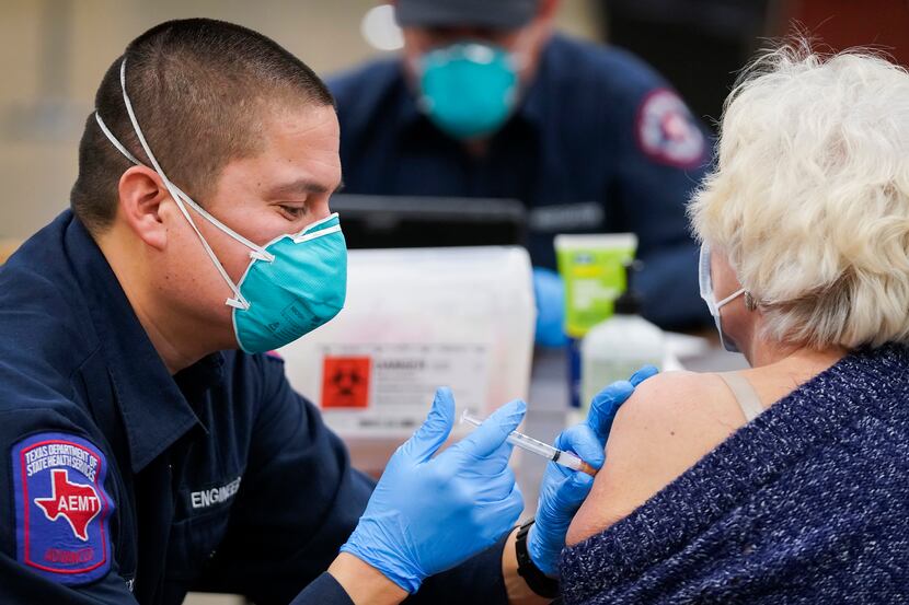 Arlington firefighter Jose Moreno administers the Moderna COVID-19 vaccine to a woman at the...