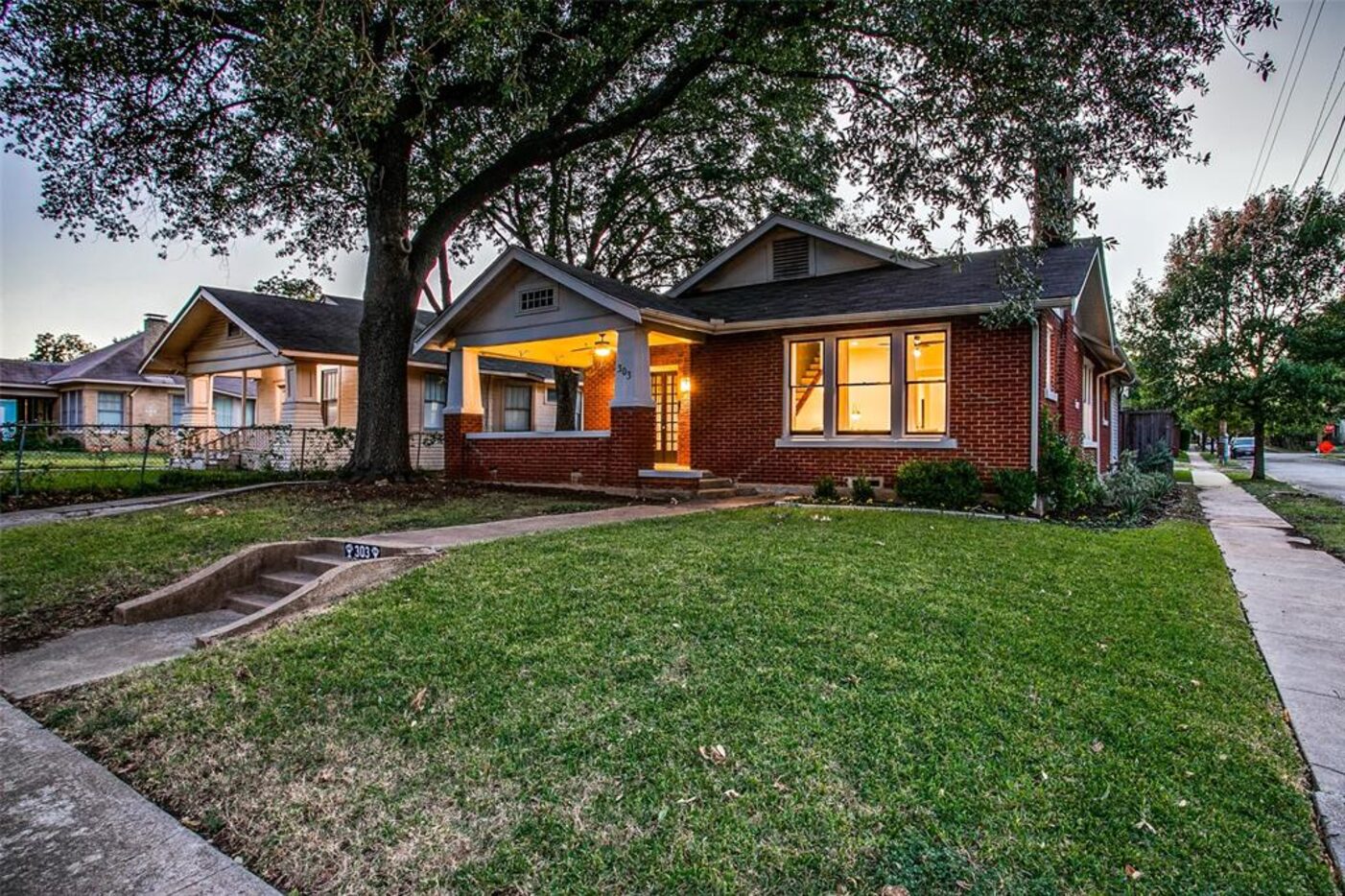 A red brick home has a front porch.