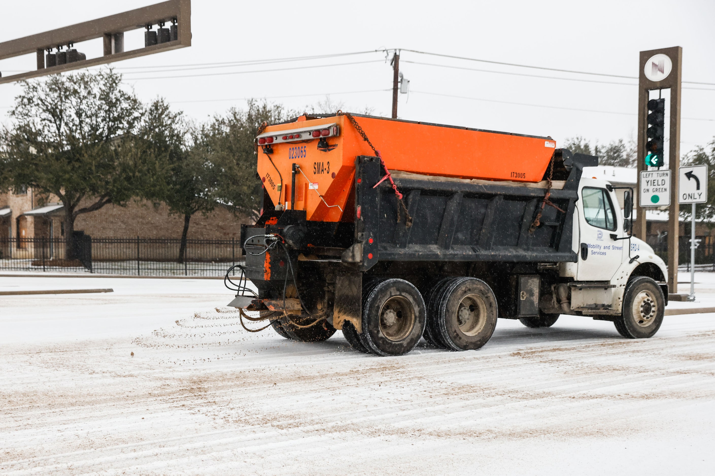 A City of Dallas truck dumps sand onto the N Hall St over US-75 as sleet falls over the...