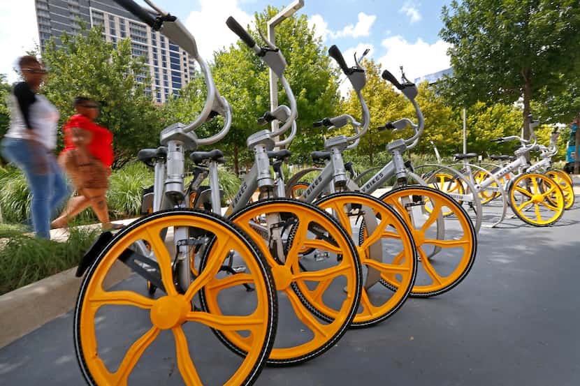 People walk by VBikes units at Klyde Warren Park in Dallas. 