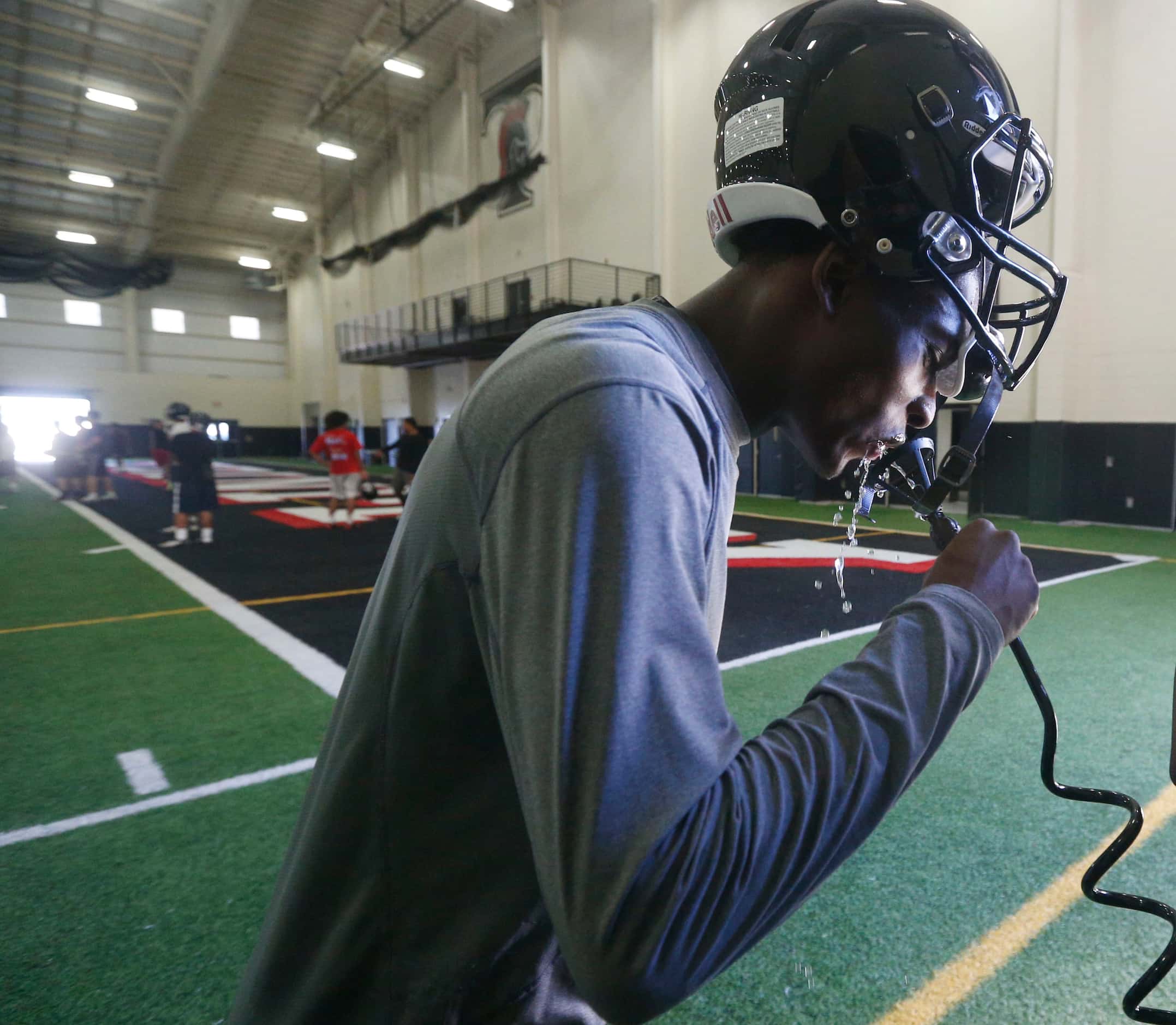 Cornerback John Davis grabs some water during Euless Trinity's first day of football...