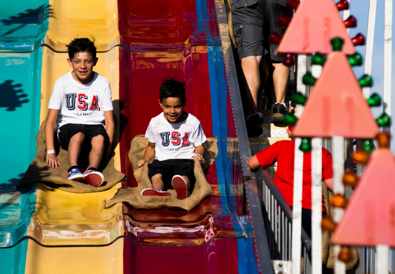 Nathan Banda, 12 and Izzic Banda, 7, slide down a giant slide during Kaboom Town festivities...