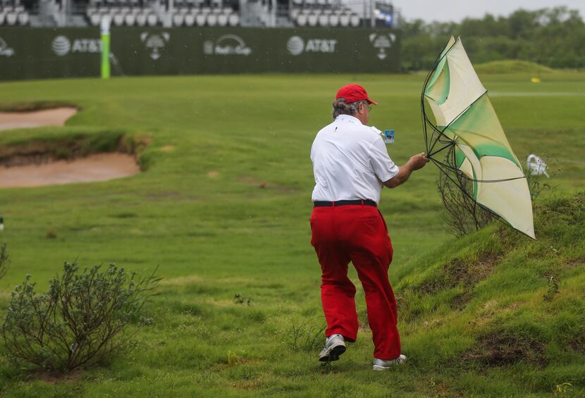 Mike McKenzie struggled with his umbrella while attempting to cross the 18th fairway after...