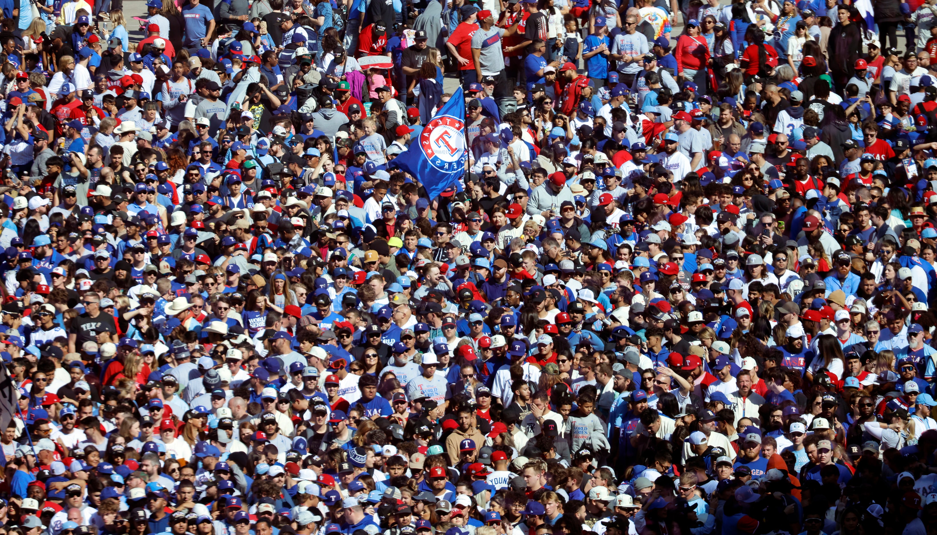 A Texas Rangers fan waves a team flag among those gathered at the World Series Victory...