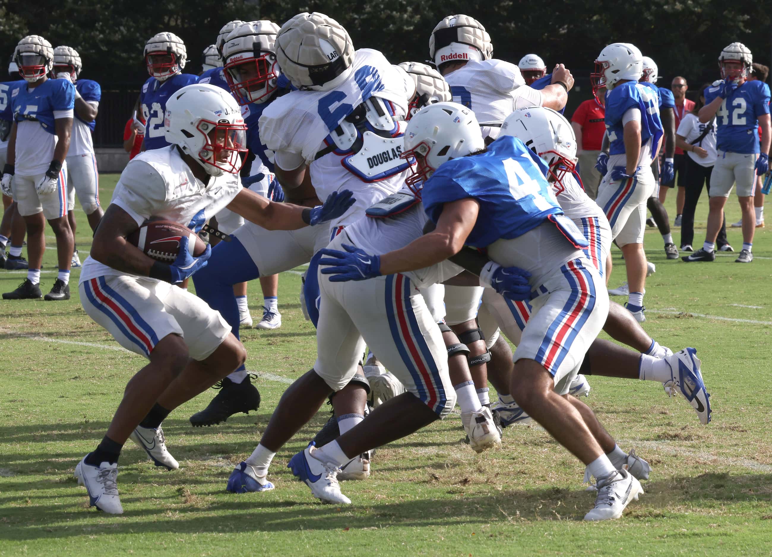 Members of the SMU Mustangs offensive line work to open up a lane for running back Jaylan...