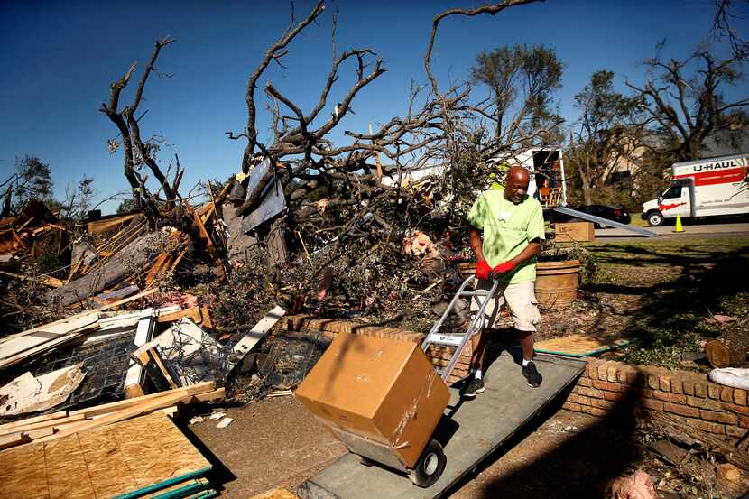JW Rodgers carts boxed up items through the tree branch-strewn front yard of Brenda...