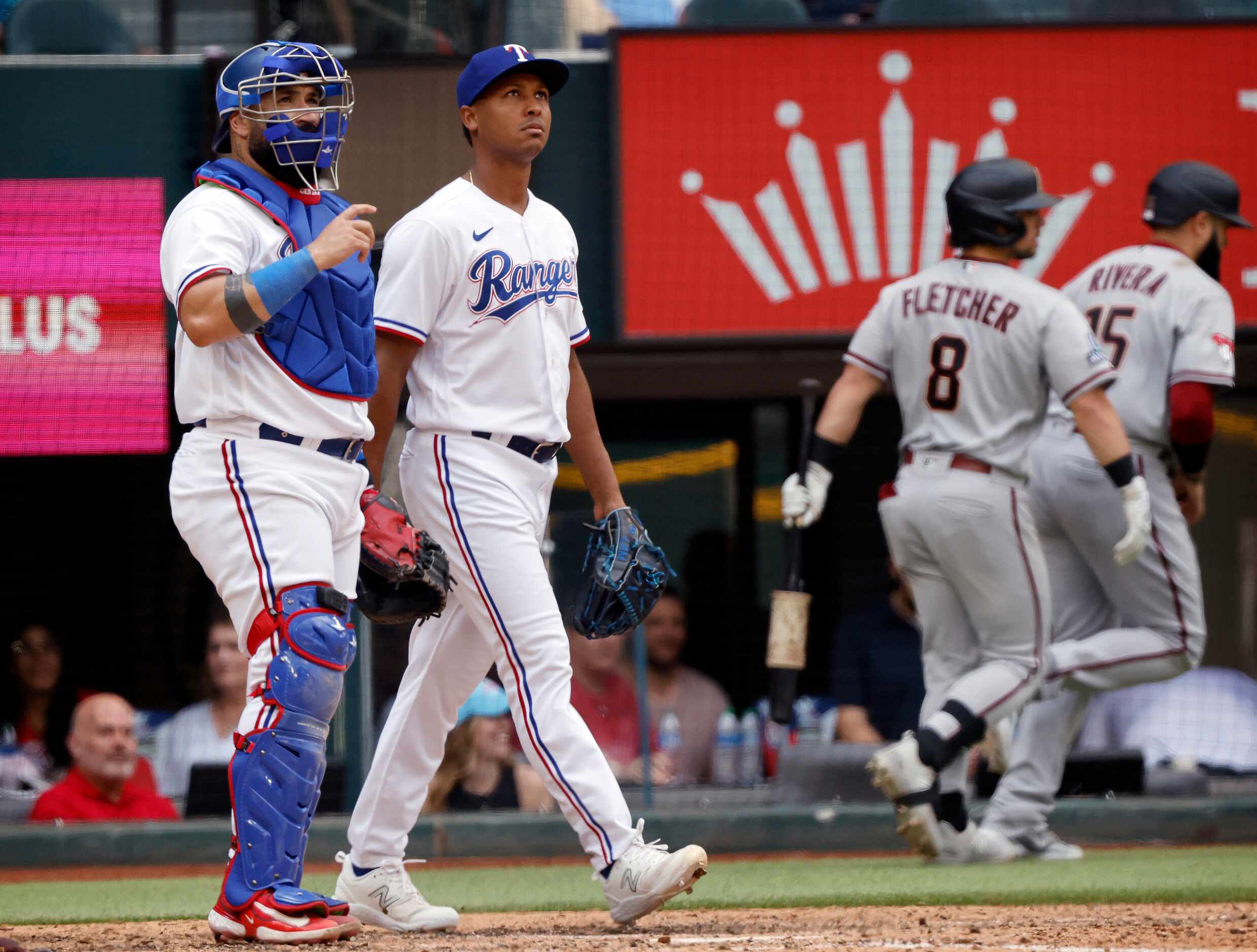 Texas Rangers relief pitcher Jose Leclerc (center) looks to the video board after giving up...