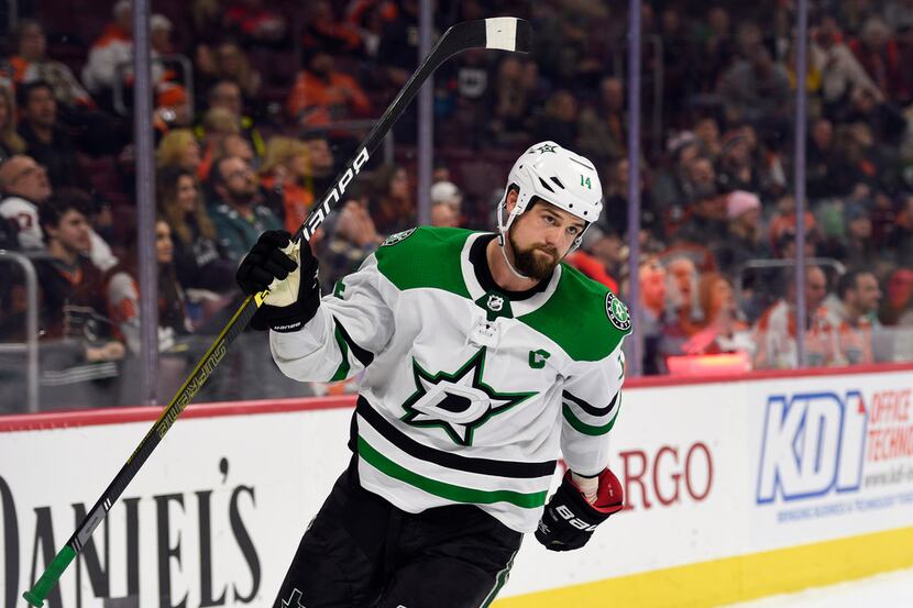 Dallas Stars' Jamie Benn raises his stick after scoring a goal during the third period of...