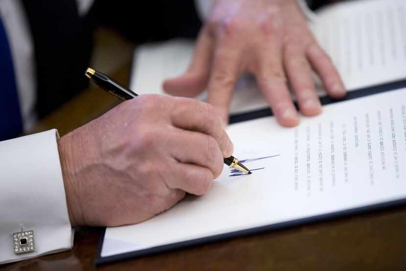 US President Donald Trump signs one of five executive orders related to the oil pipeline...
