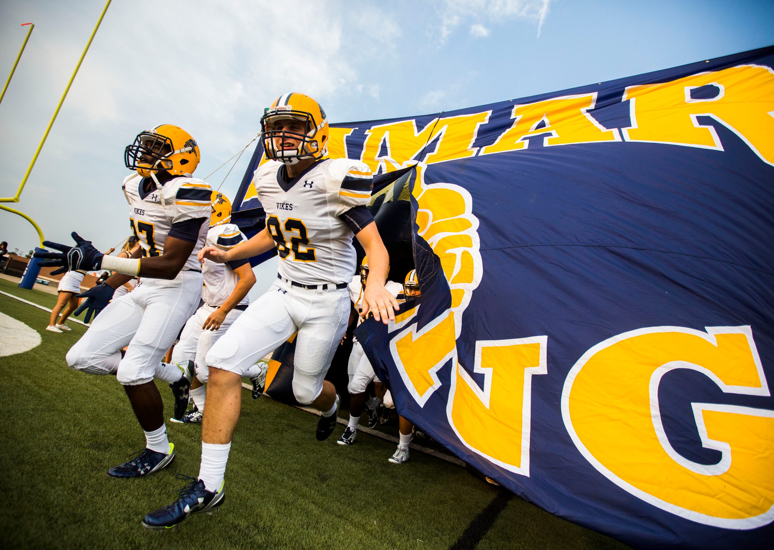 Arlington Lamar High School football players run on to the field through a banner before...