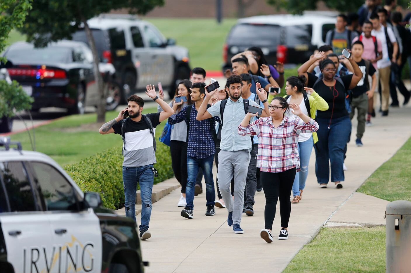 Students and faculty exit a building with their hands up after a shooting at North Lake...