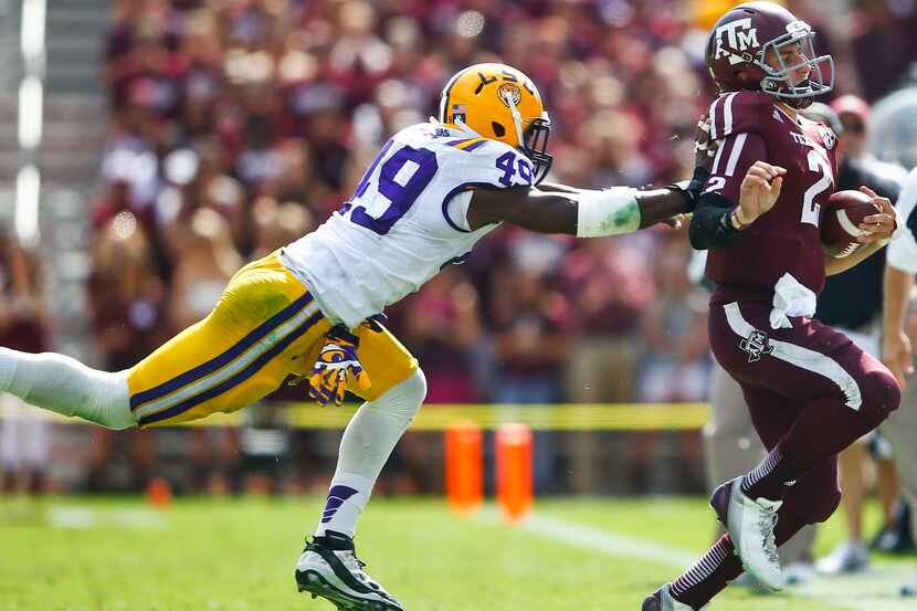Texas A&M quarterback Johnny Manziel (2) is shoved out of bounds by LSU defensive end...
