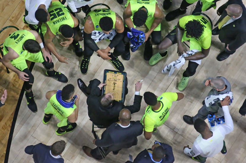 The Baylor team listens intently as head coach Scott Drew draws up a play during a time out...