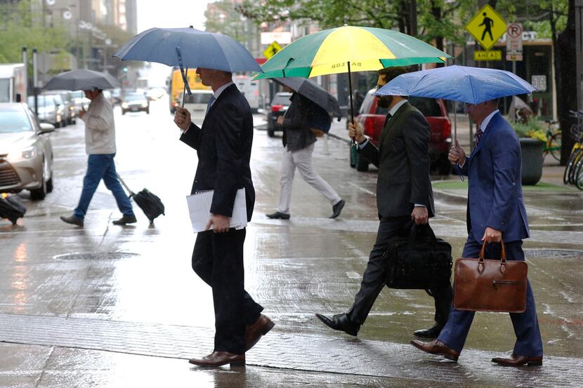 Pedestrians walk across Main St. during a rain shower in downtown Dallas, Tuesday, March 27,...
